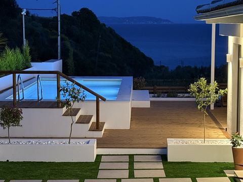 Lit pool with a sea view at dusk